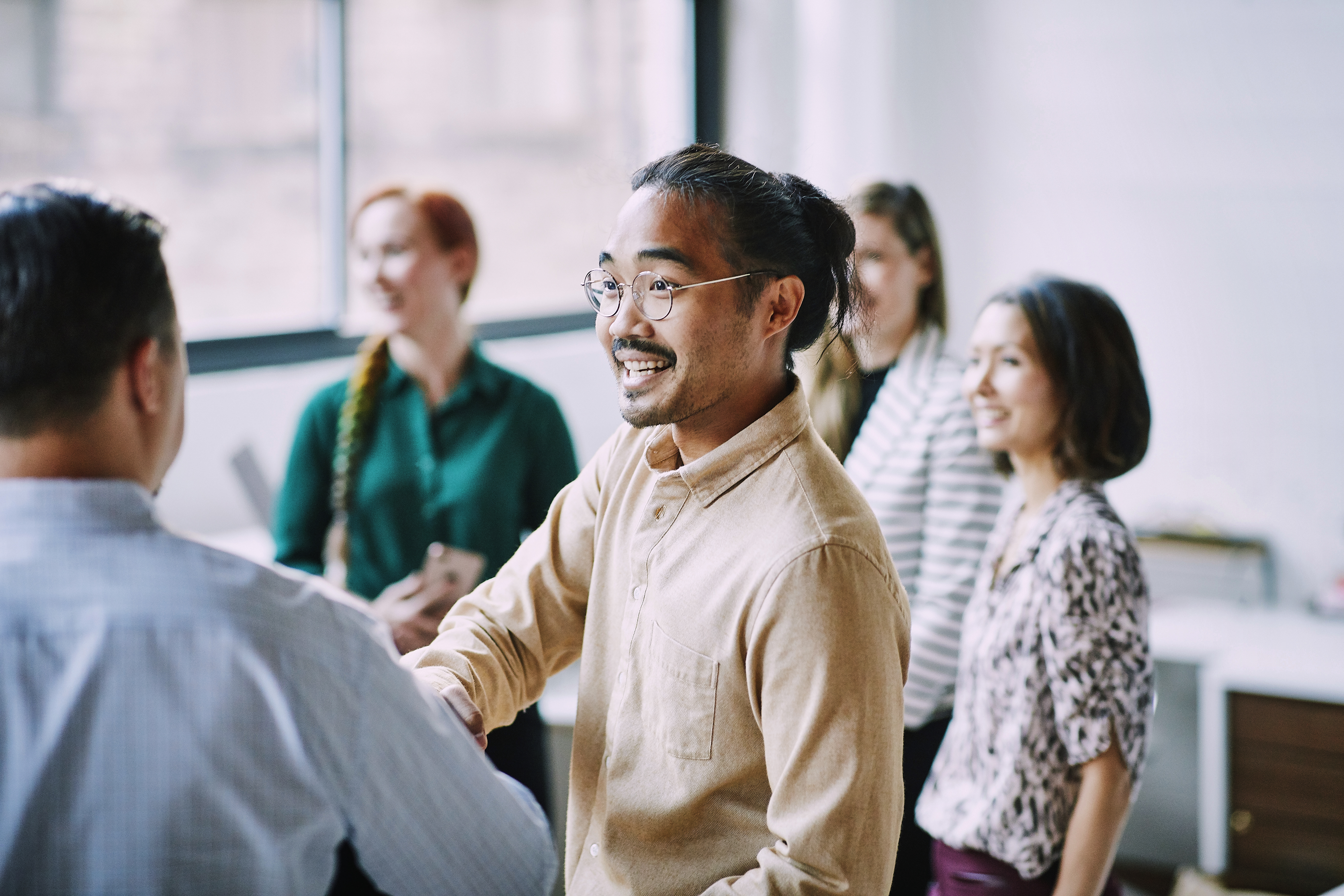 man shaking hands with three people smiling behind him